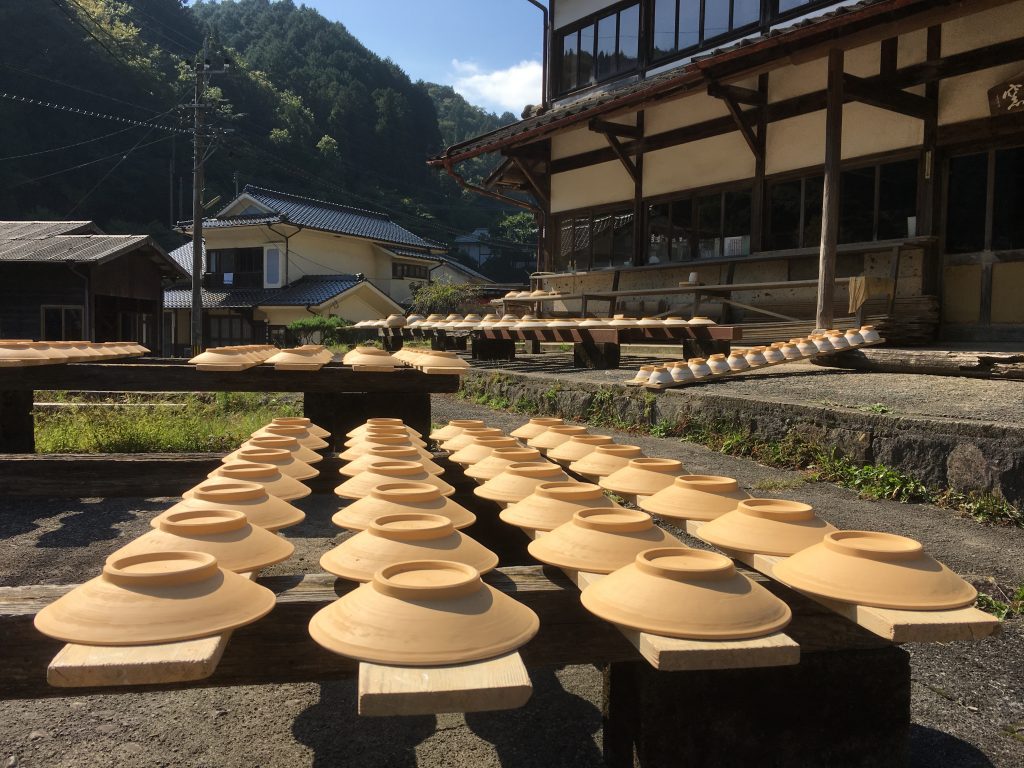 Rows of unfired ceramic bowls drying outdoors