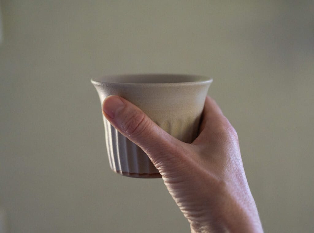 Hand holding a handmade ceramic cup by Celeste Ortelee