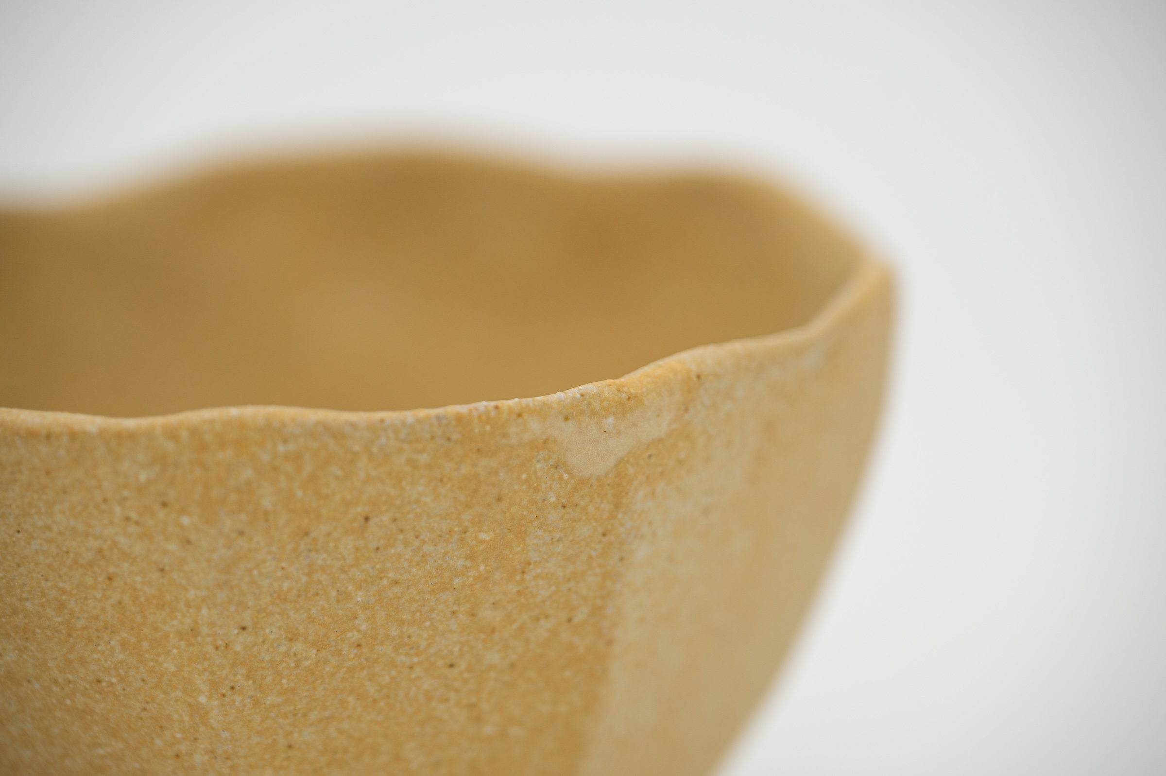 Detail of the gently irregular rim and fine ochre glaze texture of Unfolding.
